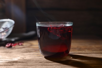 Delicious hibiscus tea in glass on wooden table, closeup