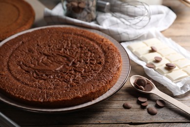 Photo of Delicious homemade sponge cake and different kinds of chocolate on wooden table, closeup