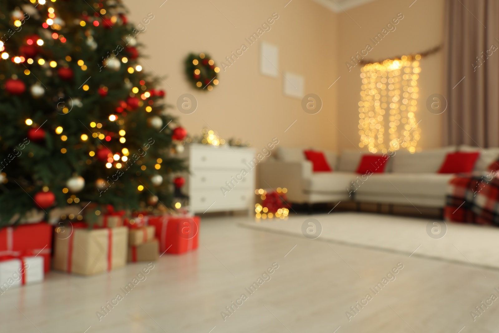 Photo of Beautiful tree decorated for Christmas, chest of drawers and sofa in room, blurred view. Interior design