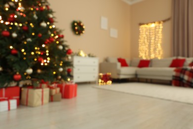 Beautiful tree decorated for Christmas, chest of drawers and sofa in room, blurred view. Interior design