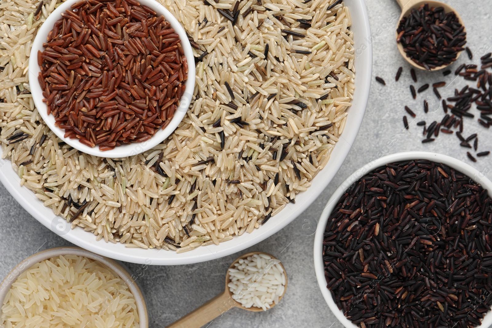 Photo of Different sorts of rice on grey table, flat lay