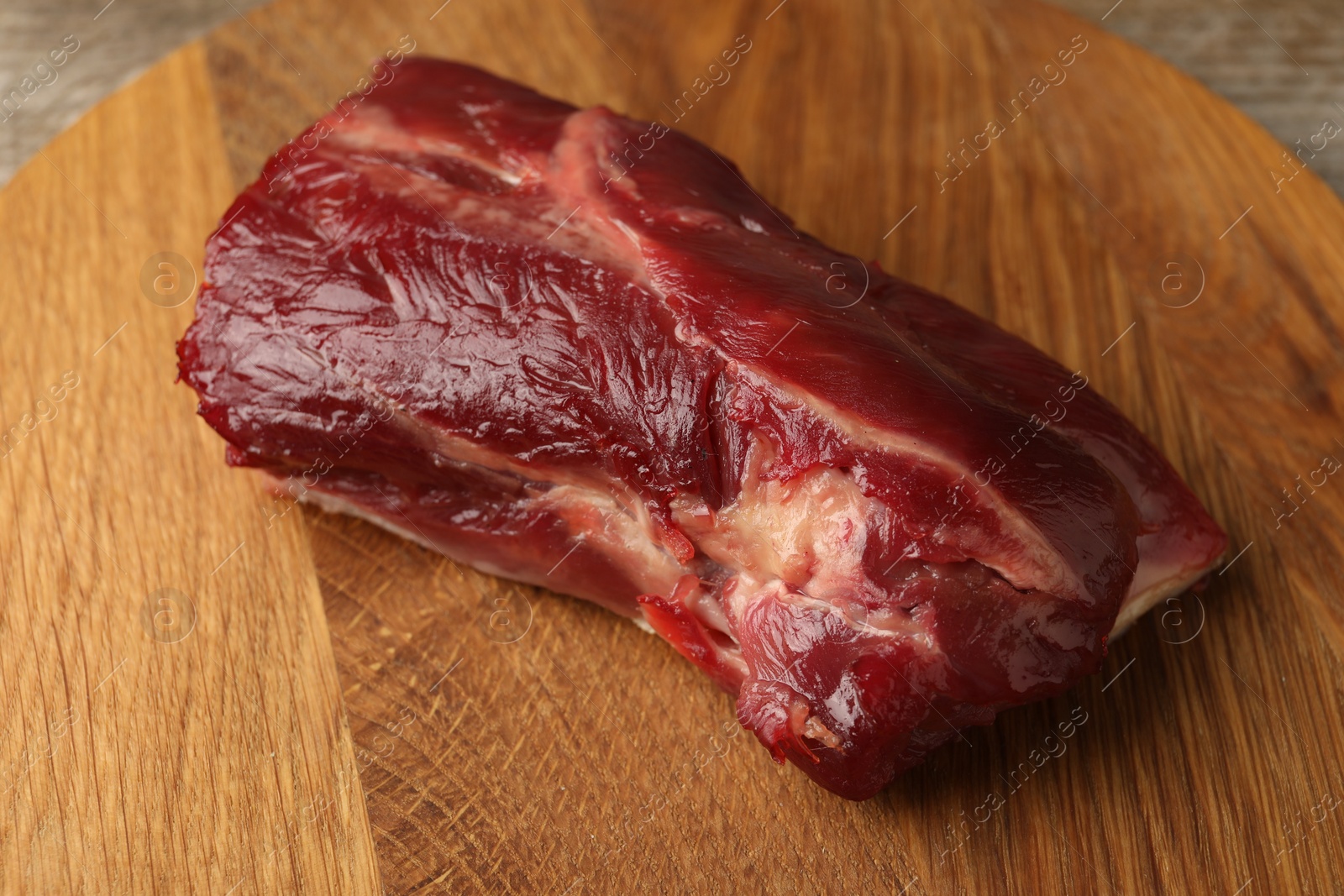 Photo of Piece of raw beef meat on wooden board, closeup