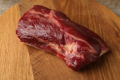 Piece of raw beef meat on wooden board, closeup