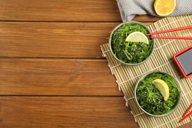 Photo of Japanese seaweed salad served on wooden table, flat lay. Space for text