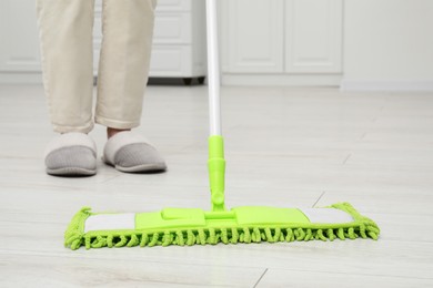 Woman cleaning dirty white parquet floor with mop indoors, closeup