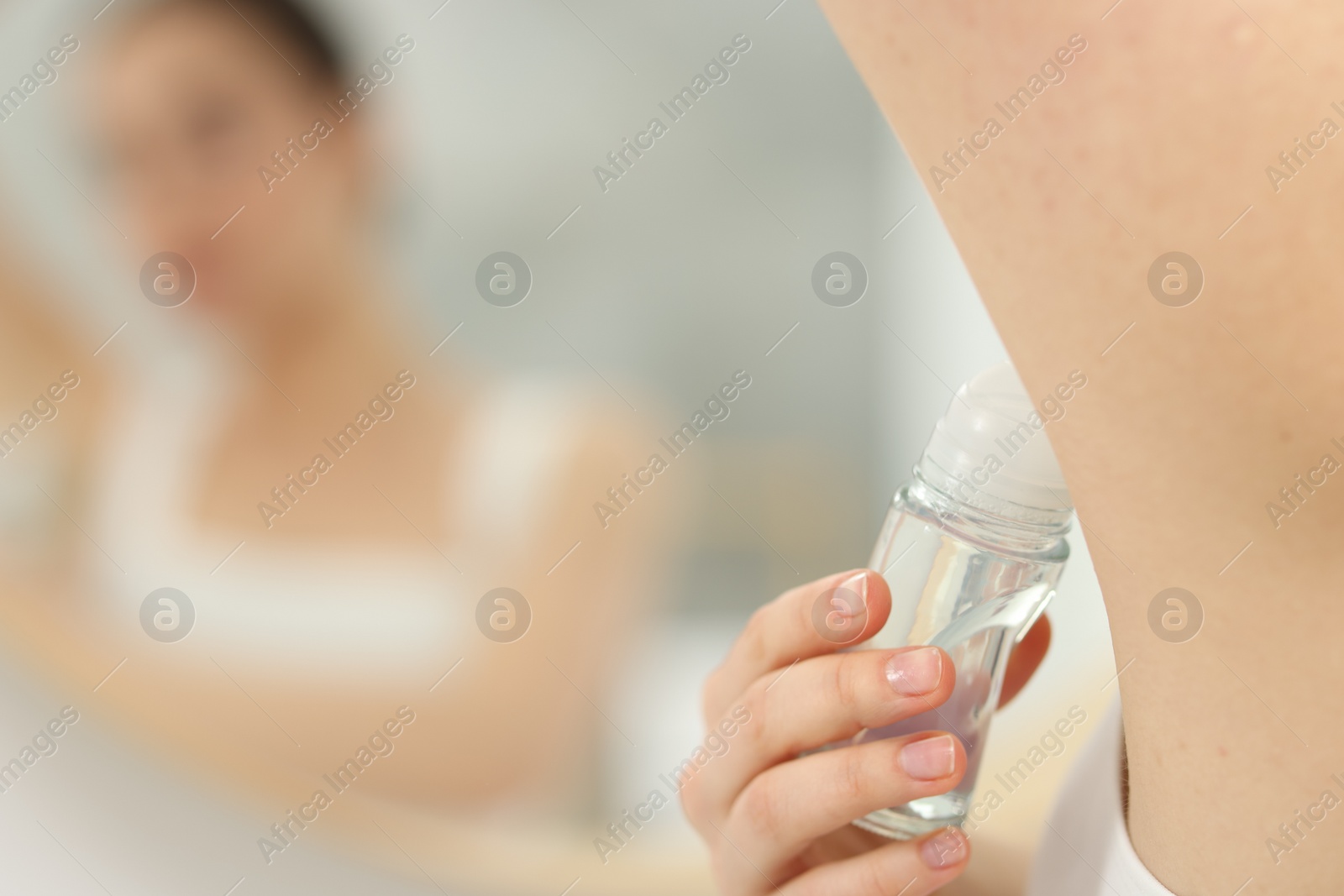 Photo of Beautiful woman applying deodorant near mirror in bathroom, selective focus