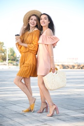 Photo of Beautiful young women in stylish dresses on city street