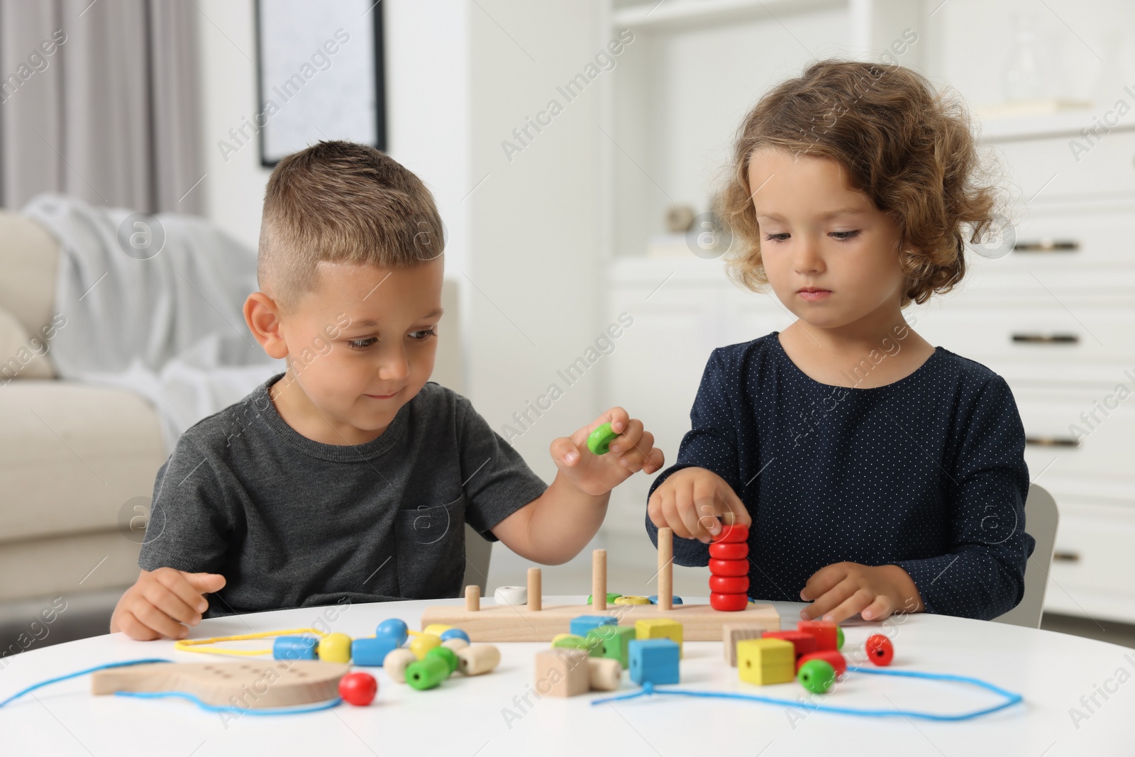 Photo of Motor skills development. Little kids playing with stacking and counting game at table indoors