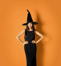 Beautiful woman wearing witch costume for Halloween party on yellow background