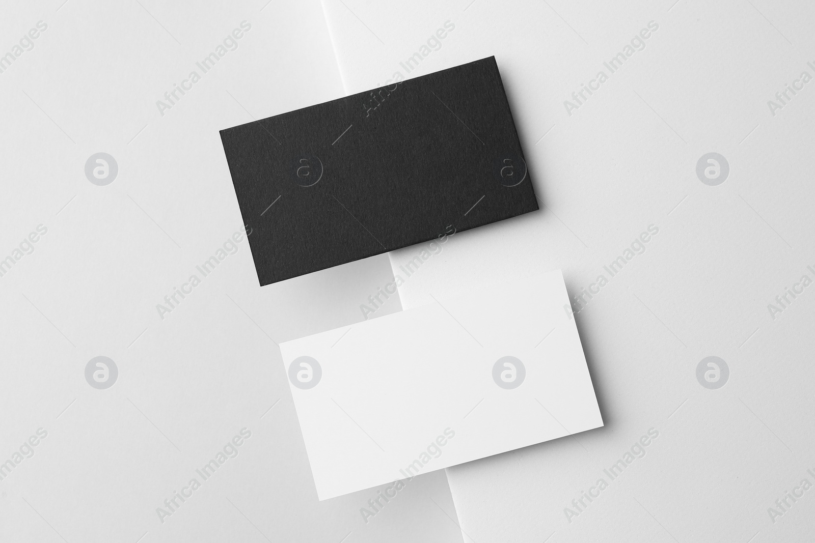 Photo of Blank black and white business cards on light background, flat lay. Mockup for design