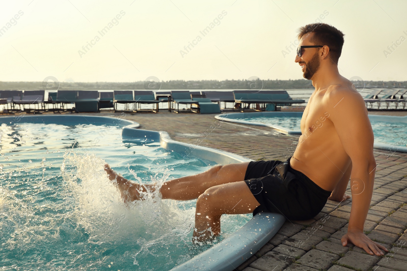 Photo of Happy man having fun near outdoor swimming pool on summer day