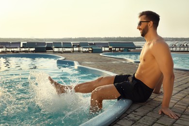 Happy man having fun near outdoor swimming pool on summer day