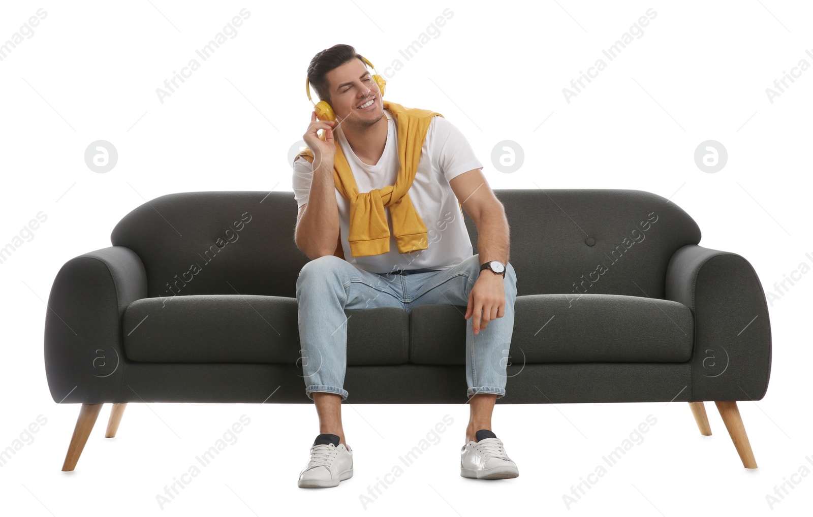 Photo of Man listening to music on comfortable grey sofa against white background