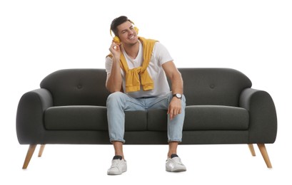 Man listening to music on comfortable grey sofa against white background