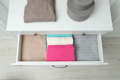 Photo of Chest of drawers with different folded clothes indoors, top view