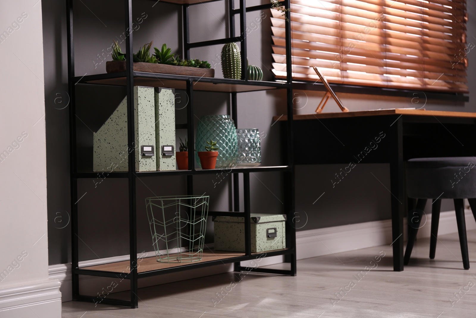 Photo of Shelving with different decor and houseplants near table in room. Interior design