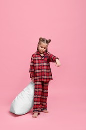 Photo of Girl in pajamas with pillow sleepwalking on pink background