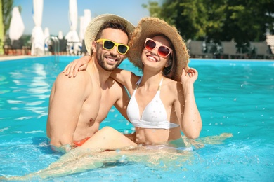 Happy couple resting in swimming pool on sunny day