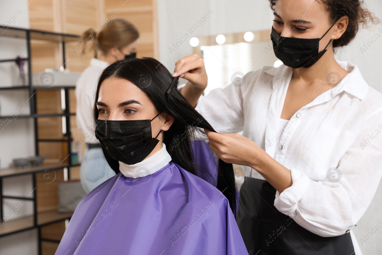 Photo of Professional stylist working with client in salon. Hairdressing services during Coronavirus quarantine