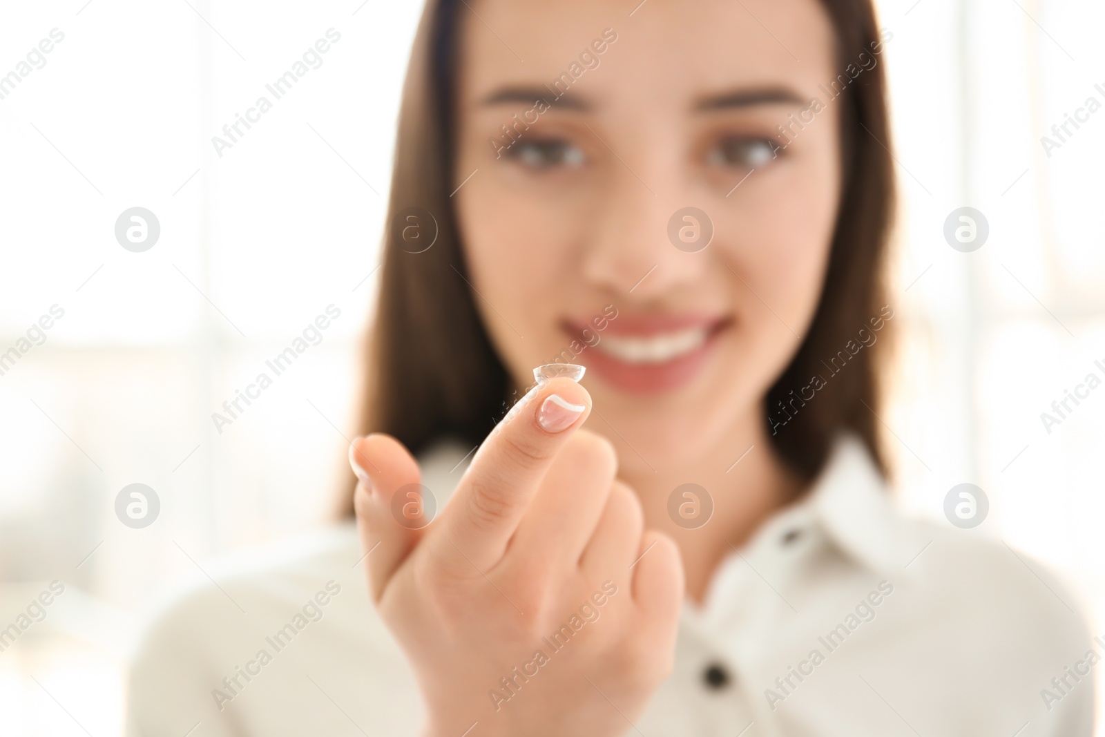 Photo of Young woman with contact lens on light background