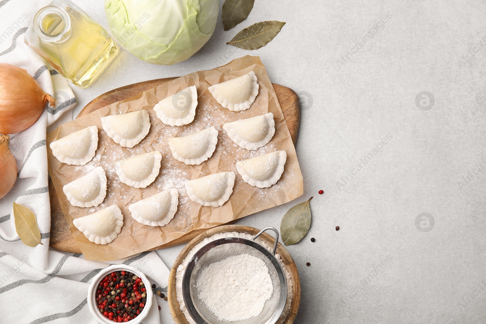 Photo of Raw dumplings (varenyky) with tasty filling and ingredients on light grey table, flat lay. Space for text