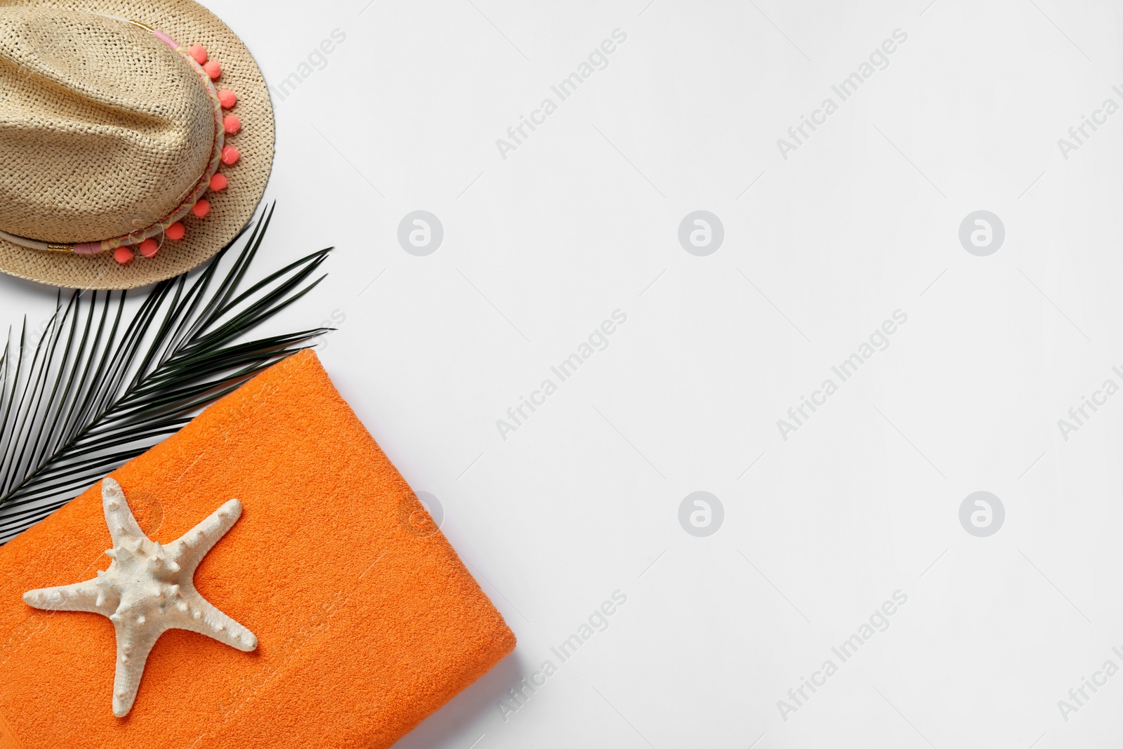 Photo of Beach towel and straw hat on light background, flat lay. Space for text