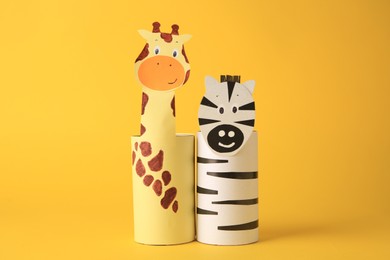 Toy giraffe and zebra made from toilet paper hubs on yellow background. Children's handmade ideas