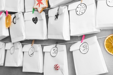 Advent calendar with gifts hanging on grey wall, closeup. Christmas season