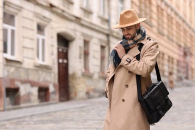 Photo of Smiling man in warm scarf on city street. Space for text