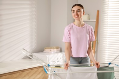 Photo of Woman hanging different apparel on clothes airer in bathroom