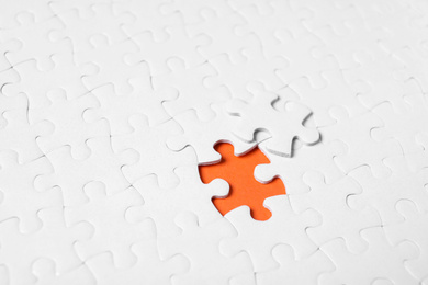 Photo of Blank white puzzle with separated piece on orange background
