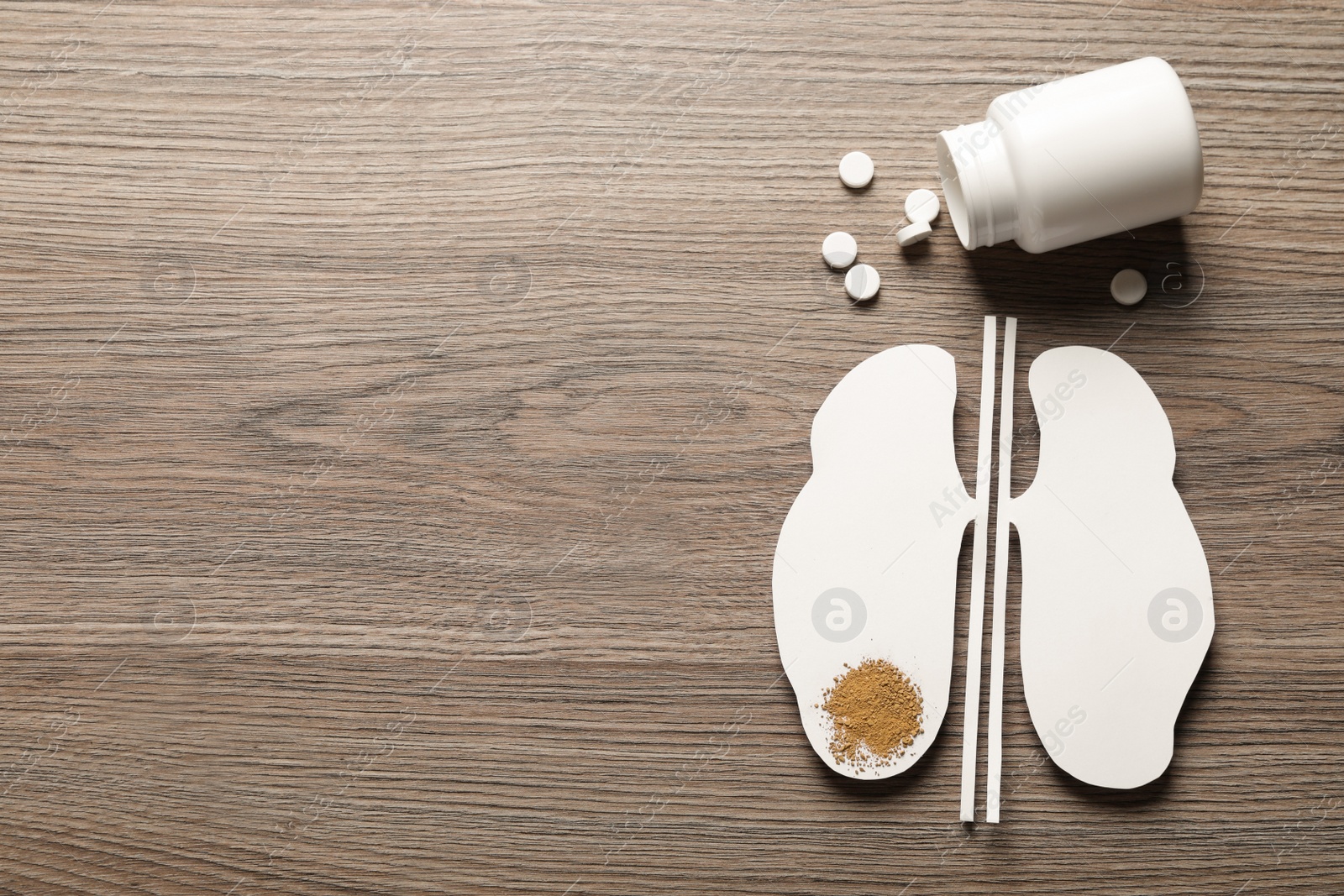 Photo of Paper cutout, sand and pills on wooden table, flat lay with space for text. Kidney stone disease