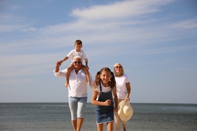 Photo of Cute little children with grandparents spending time together near sea