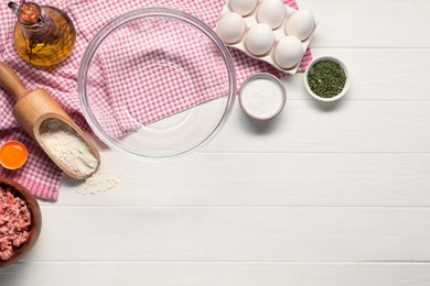 Bowl and different products on white wooden table, flat lay. Space for text