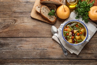 Photo of Bowl of tasty turnip soup with bread and ingredients on wooden table, flat lay. Space for text