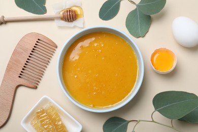 Photo of Homemade hair mask in bowl, ingredients and bamboo comb on beige background, flat lay