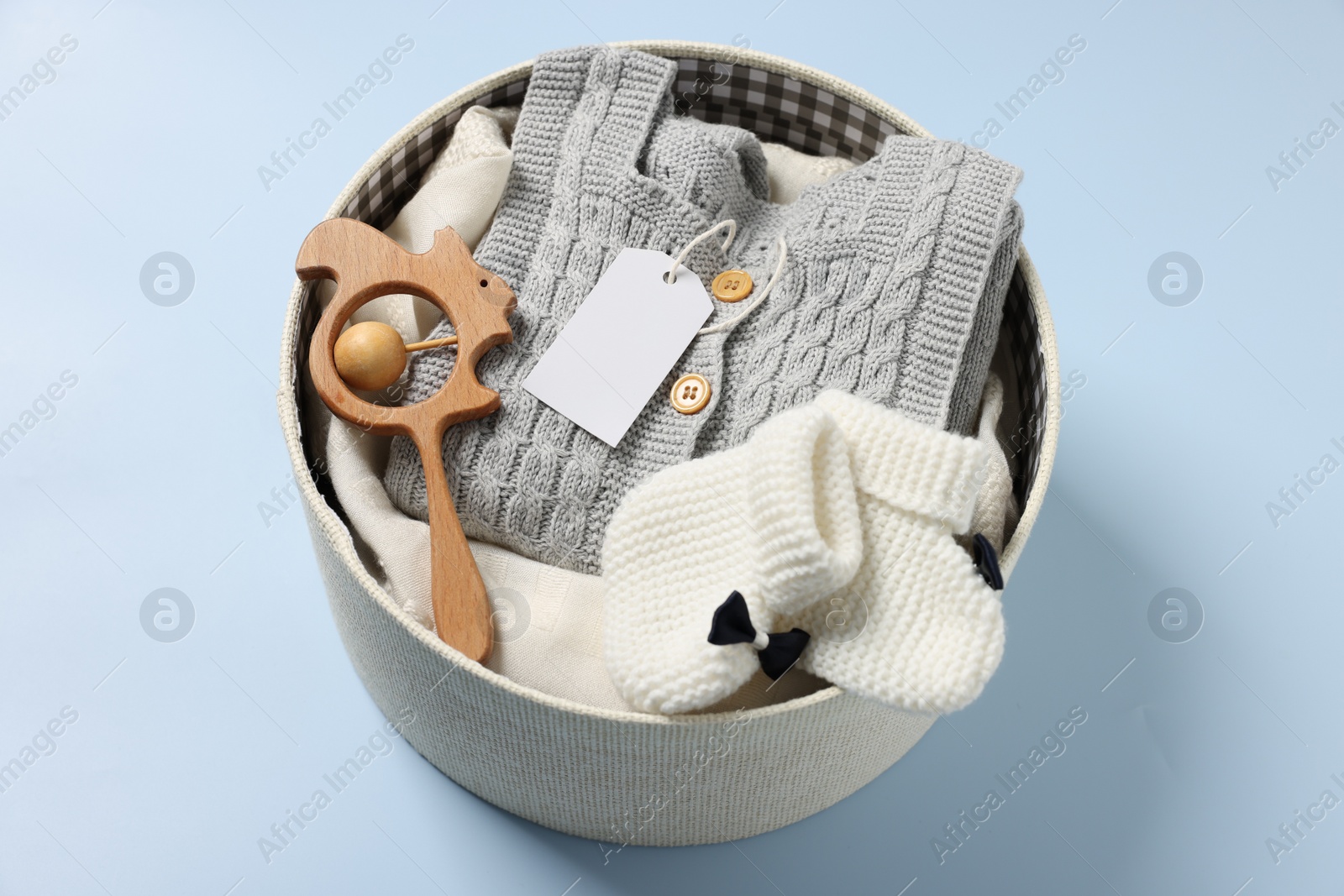 Photo of Different baby accessories and clothes in box on light blue background, above view