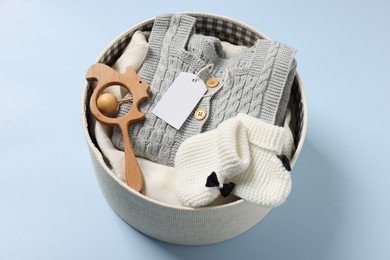 Photo of Different baby accessories and clothes in box on light blue background, above view