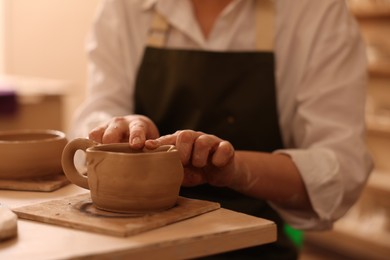 Photo of Pottery crafting. Woman sculpting with clay at table indoors, closeup