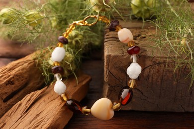 Stylish presentation of beautiful bracelet with gemstones on wooden table, closeup