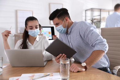 Coworkers with masks in office. Protective measure during COVID-19 pandemic