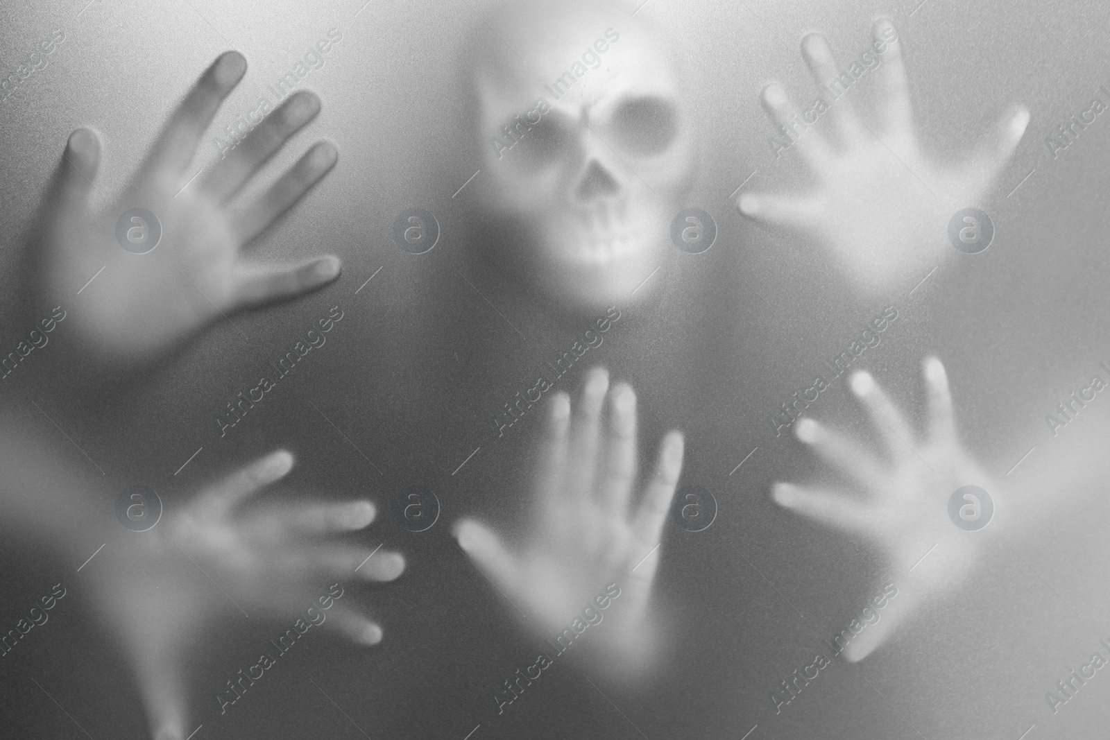 Photo of Silhouette of creepy ghost with skull behind cloth. Black and white effect