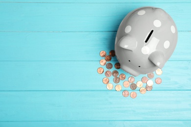 Photo of Piggy bank with coins and space for text on table, top view