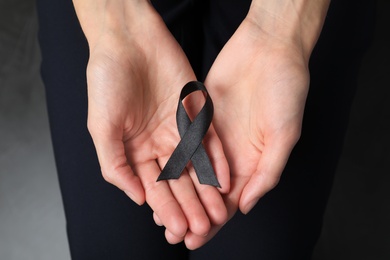 Photo of Young woman holding black ribbon, closeup. Funeral symbol