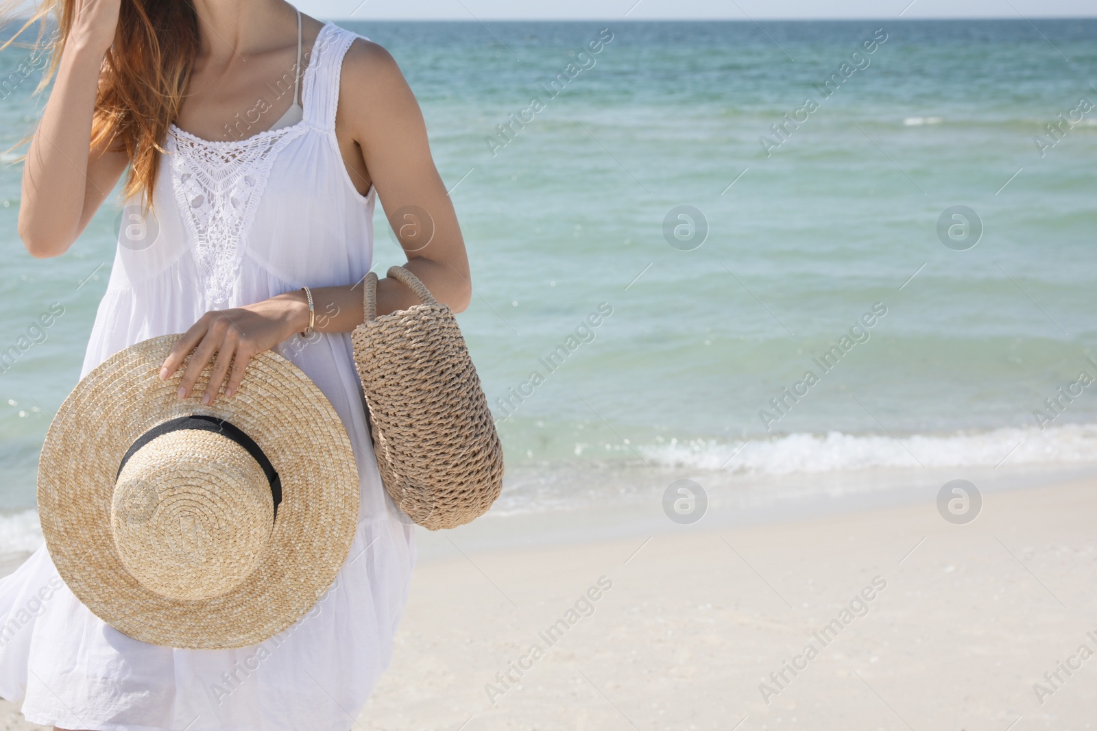 Photo of Woman with beach bag and straw hat near sea, closeup