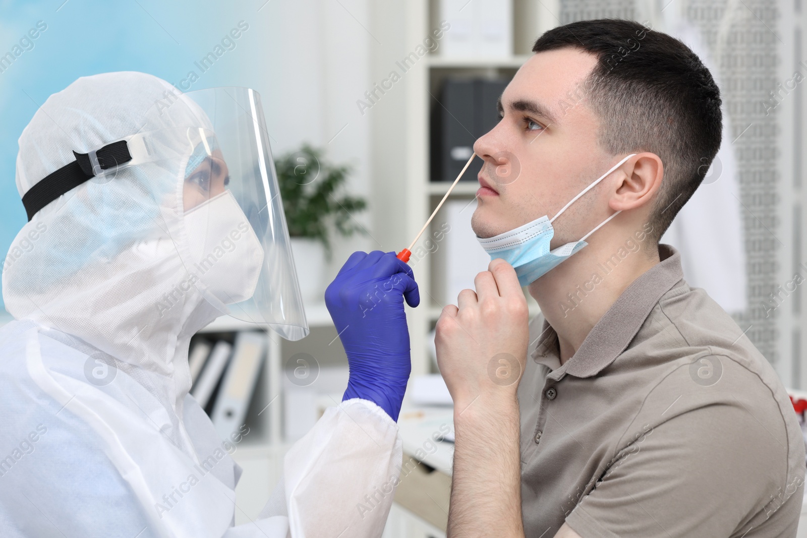 Photo of Laboratory testing. Doctor in uniform taking sample from patient's nose with cotton swab at hospital