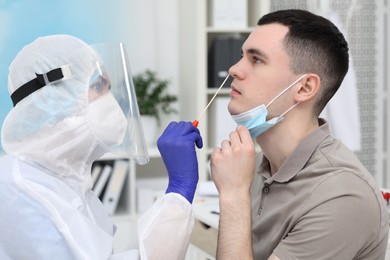 Laboratory testing. Doctor in uniform taking sample from patient's nose with cotton swab at hospital