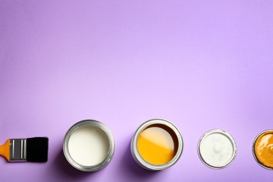 Photo of Open paint cans, brush and space for text on color background, top view