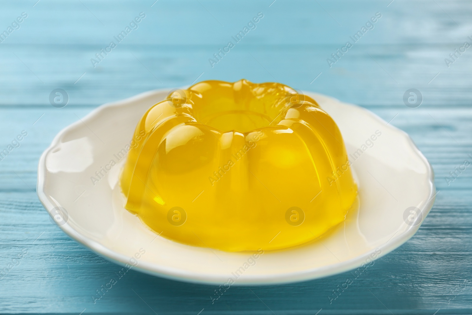 Photo of Plate of tasty fruit jelly on blue wooden table, closeup