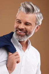 Portrait of smiling man with beautiful hairstyle on light brown background